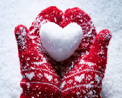  Hands with mittens holding a heart shaped snowball.