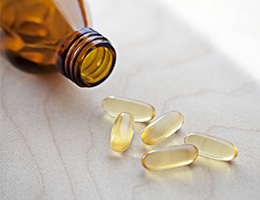 A pill bottle on its side with several translucent pills spilling out on a table.