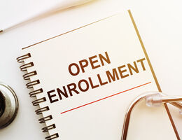 A stethoscope on a notebook labeled "open enrollment."
