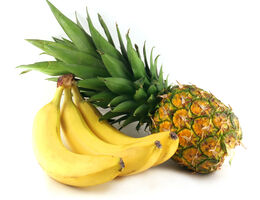 A pineapple leaning on a hand of bananas. 