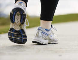 A woman's feet walking away, wearing athletic shoes.