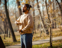 A man wearing headphones does tai chi outdoors.
