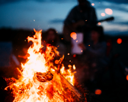 A campfire at night with a silhouette in the background.