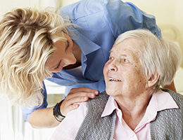 A young woman leans over the shoulder of a smiling older woman.