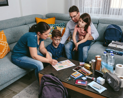  A family gathers on a couch to look at a map. An emergency kit is open on the table.