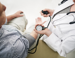 A medical professional takes a man’s blood pressure.