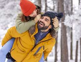 A man gives a woman a piggyback through snowy woods