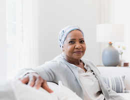 A woman wearing a head covering sits on a couch.