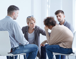 A woman talks to two men at a support group.