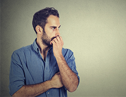 A worried man holding his hand to his mouth. 